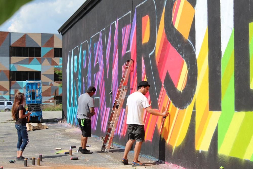 two men painting on wall during daytime