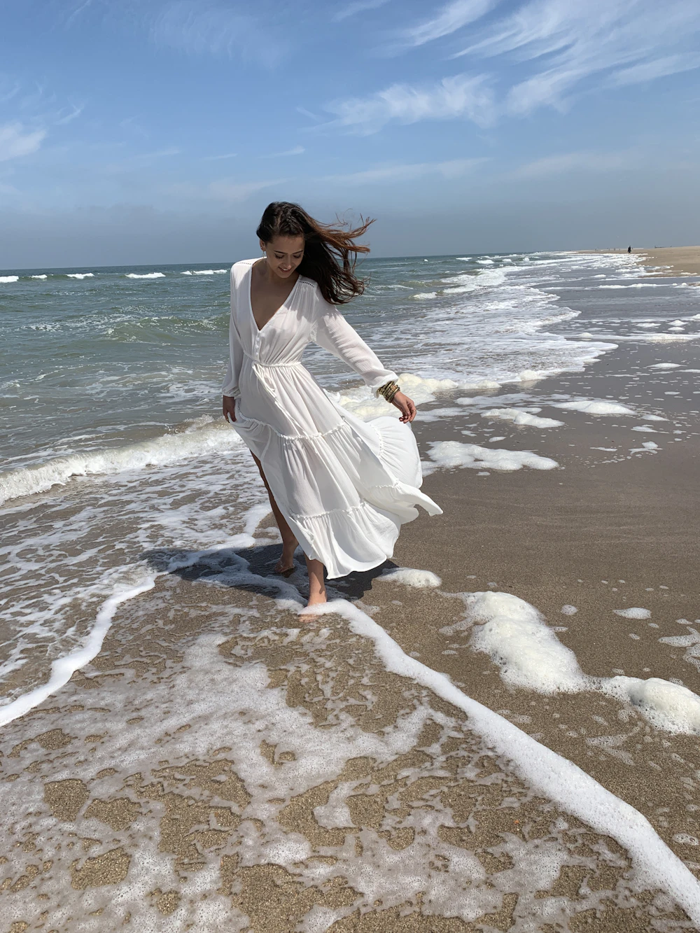 Woman walking through ocean waves in a flowy white chiffon dress
