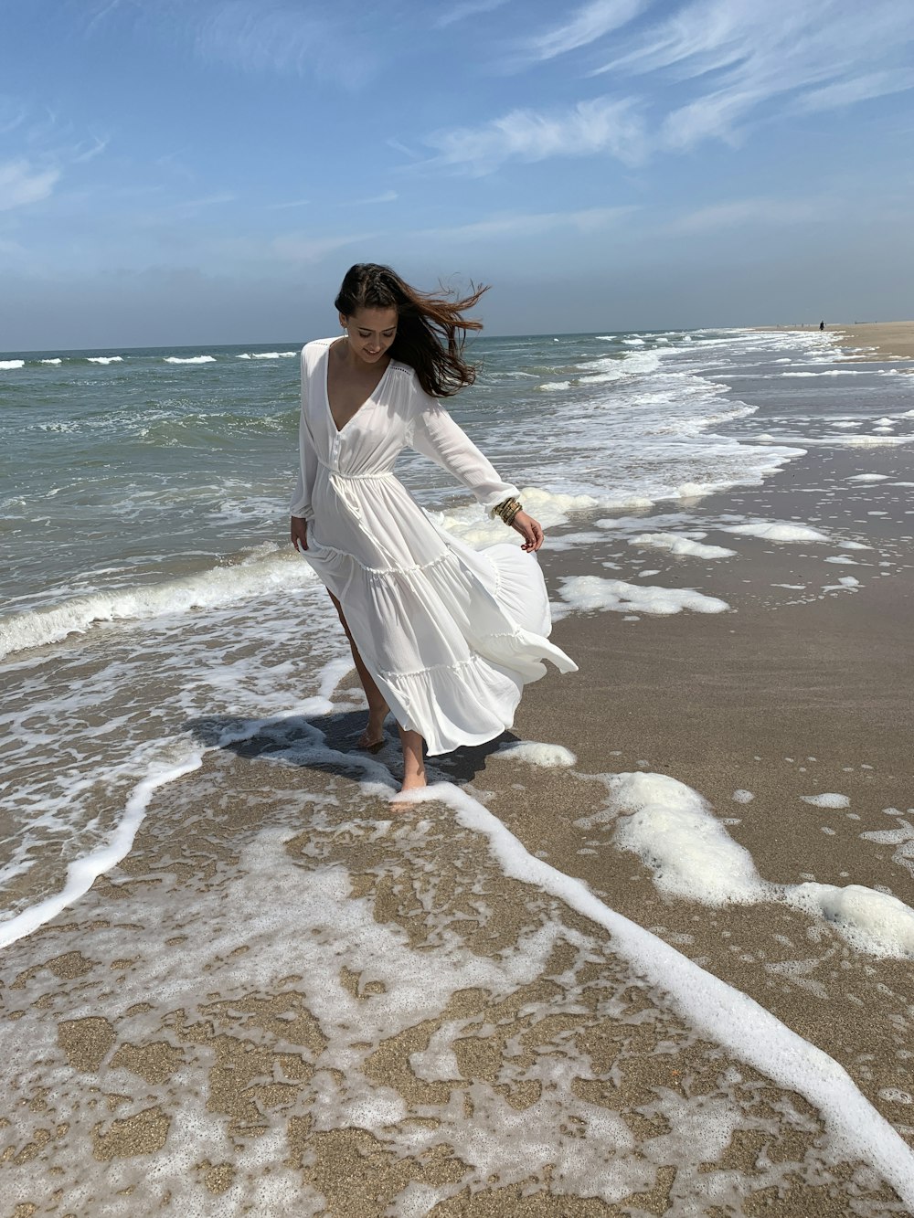 Frau trägt weißes Maxikleid am Strand