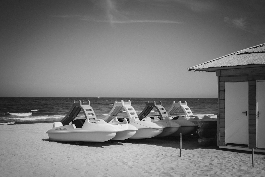 grayscale photo of watercrafts near house on beach