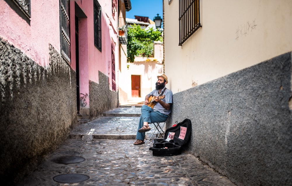 sitting man playing guitar with open guitar bag on side on allway