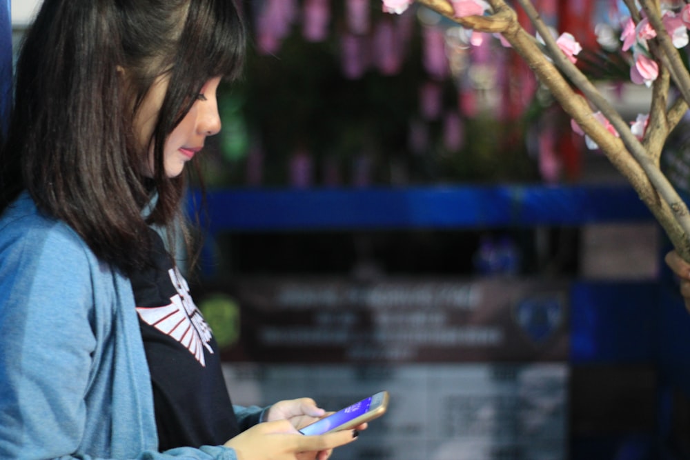 woman wearing blue cardigan holding smartphone