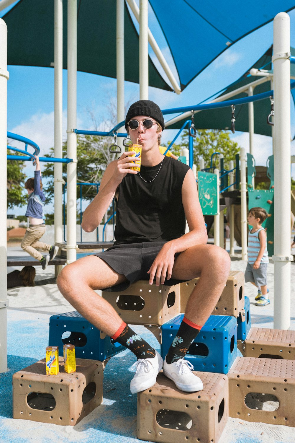 man sitting on pile of stools drinking from juicebox