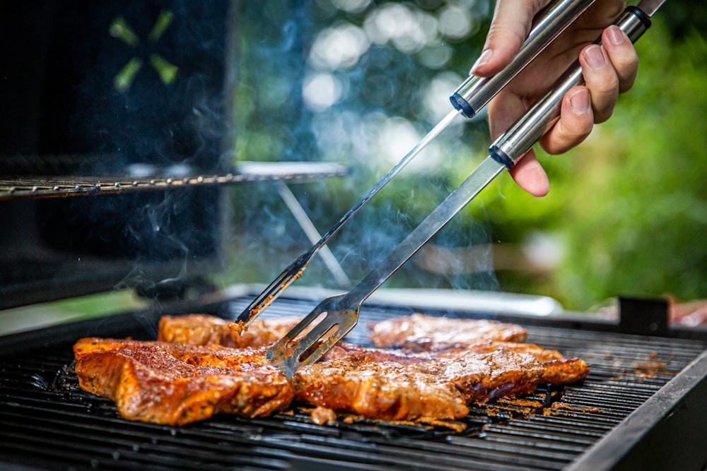 person holding gray tongs on barbecue