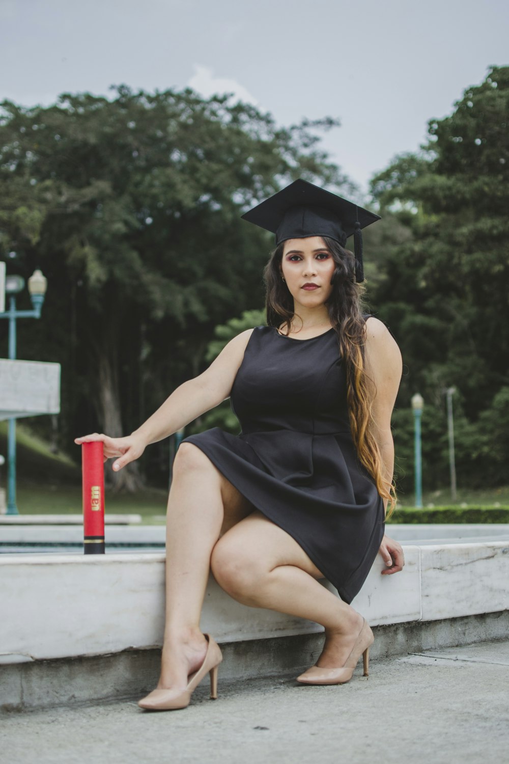 woman in academic gown sitting beside pool