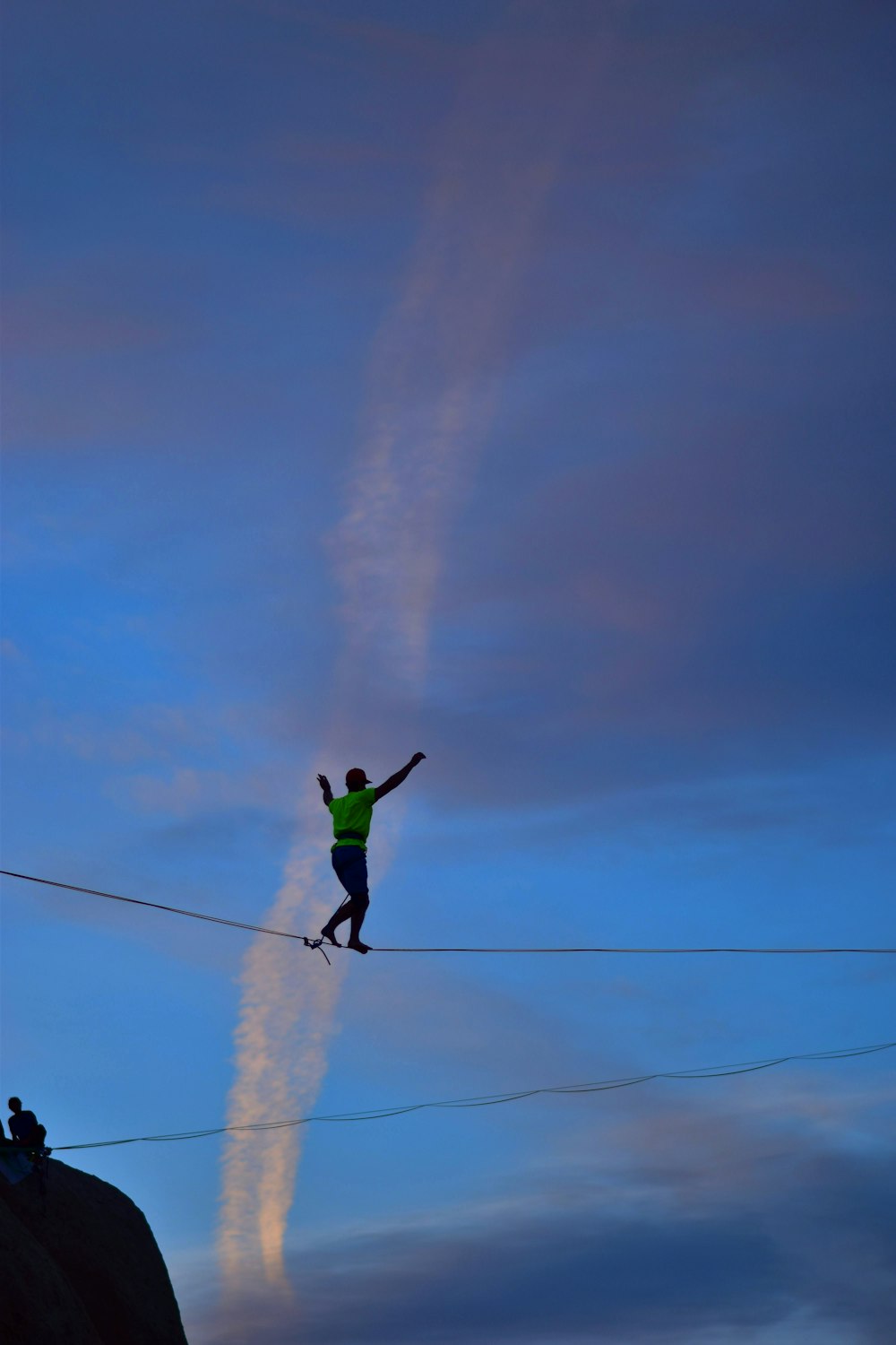 man wearing green crew-neck shirt walking on rope