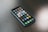 A smartphone with a variety of apps displayed on its screen, placed on a dark wooden surface. The screen shows a mix of social media, entertainment, and utility apps, neatly organized into folders and individual icons.