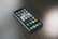A smartphone with a variety of apps displayed on its screen, placed on a dark wooden surface. The screen shows a mix of social media, entertainment, and utility apps, neatly organized into folders and individual icons.