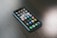 A smartphone with a variety of apps displayed on its screen, placed on a dark wooden surface. The screen shows a mix of social media, entertainment, and utility apps, neatly organized into folders and individual icons.