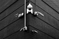 A selection of security cameras are mounted on a brick wall, arranged at the corner of the building. The wall is composed of dark bricks, creating a stark contrast with the white and metallic colors of the cameras. The layout includes various types of cameras, each pointing in different directions.