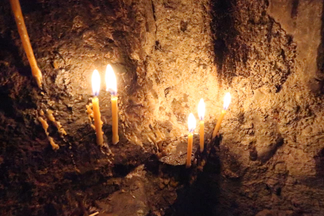 Candlelight flickering on a wall filled with pinned clues and red thread connections