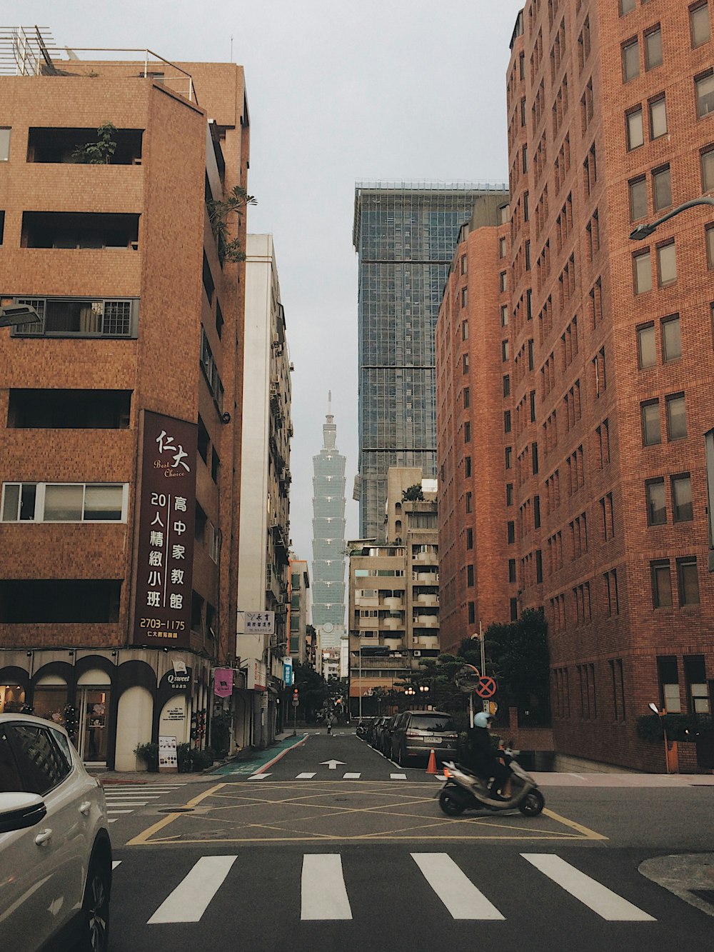 person riding gray motor scooter across buildings