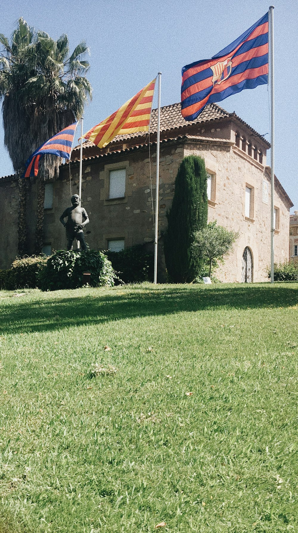 Drei verschiedene Fahnen wehen an Stangen neben der Statue