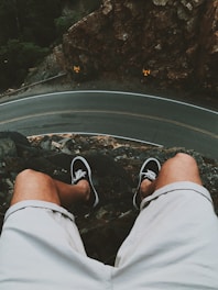 man sitting on cliff near road