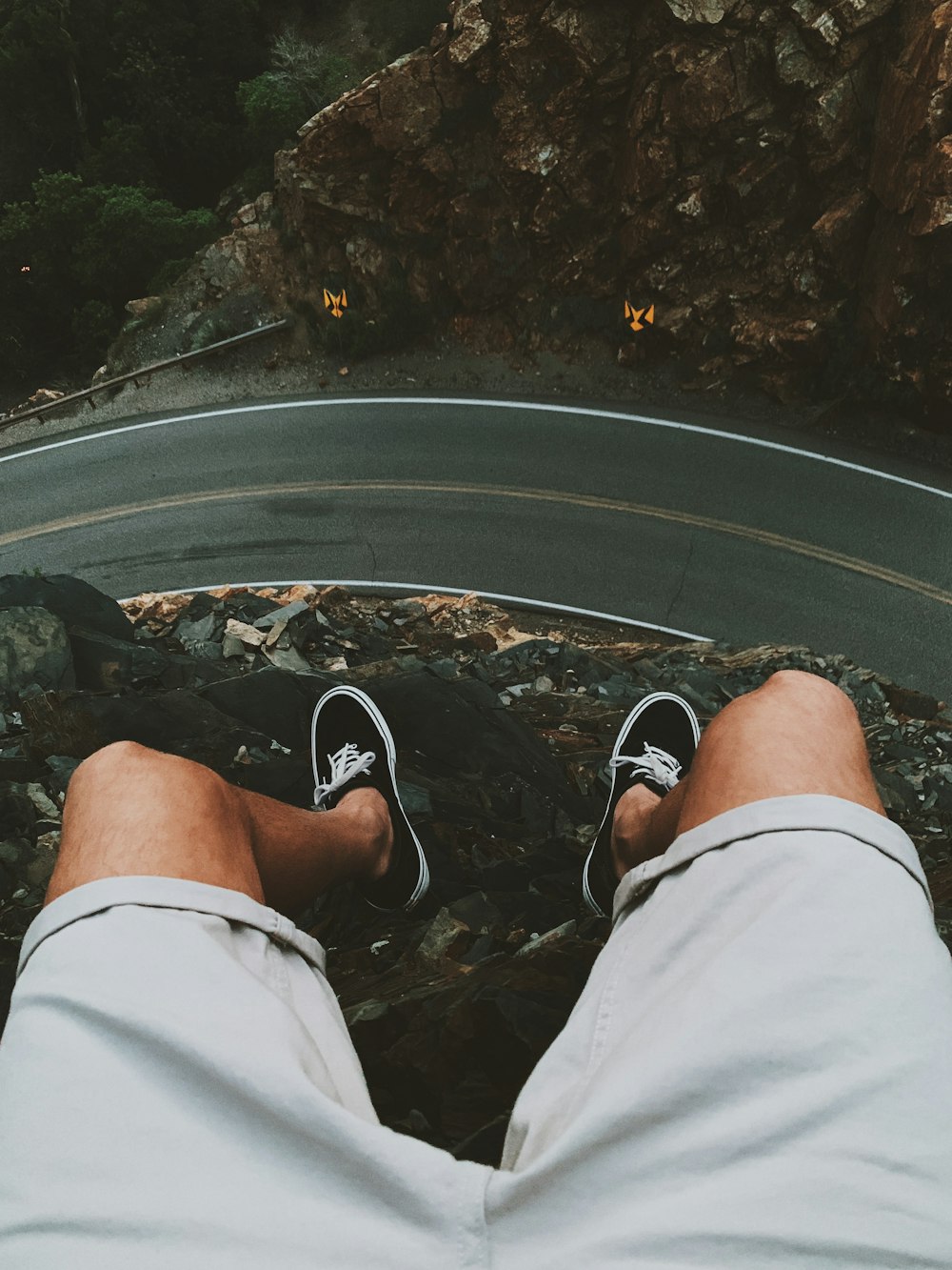 man sitting on cliff near road