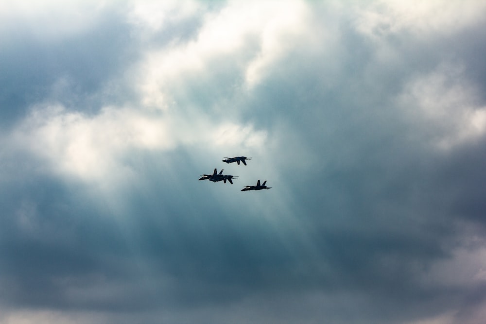 a group of fighter jets flying through a cloudy sky