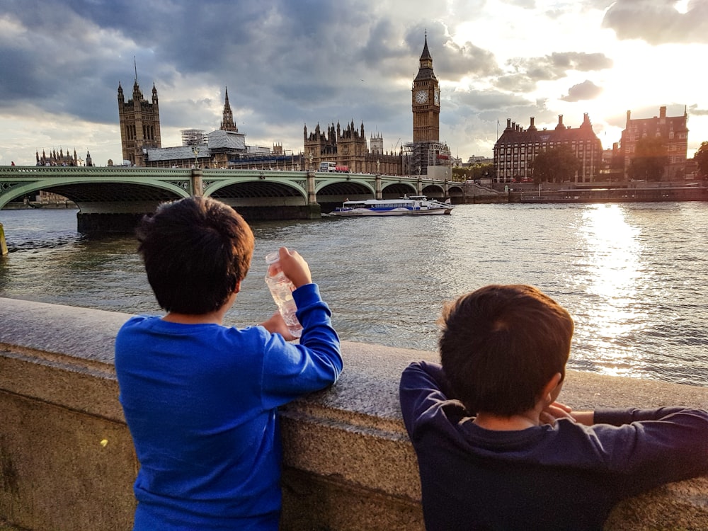 two boys watching golden hour near bridge