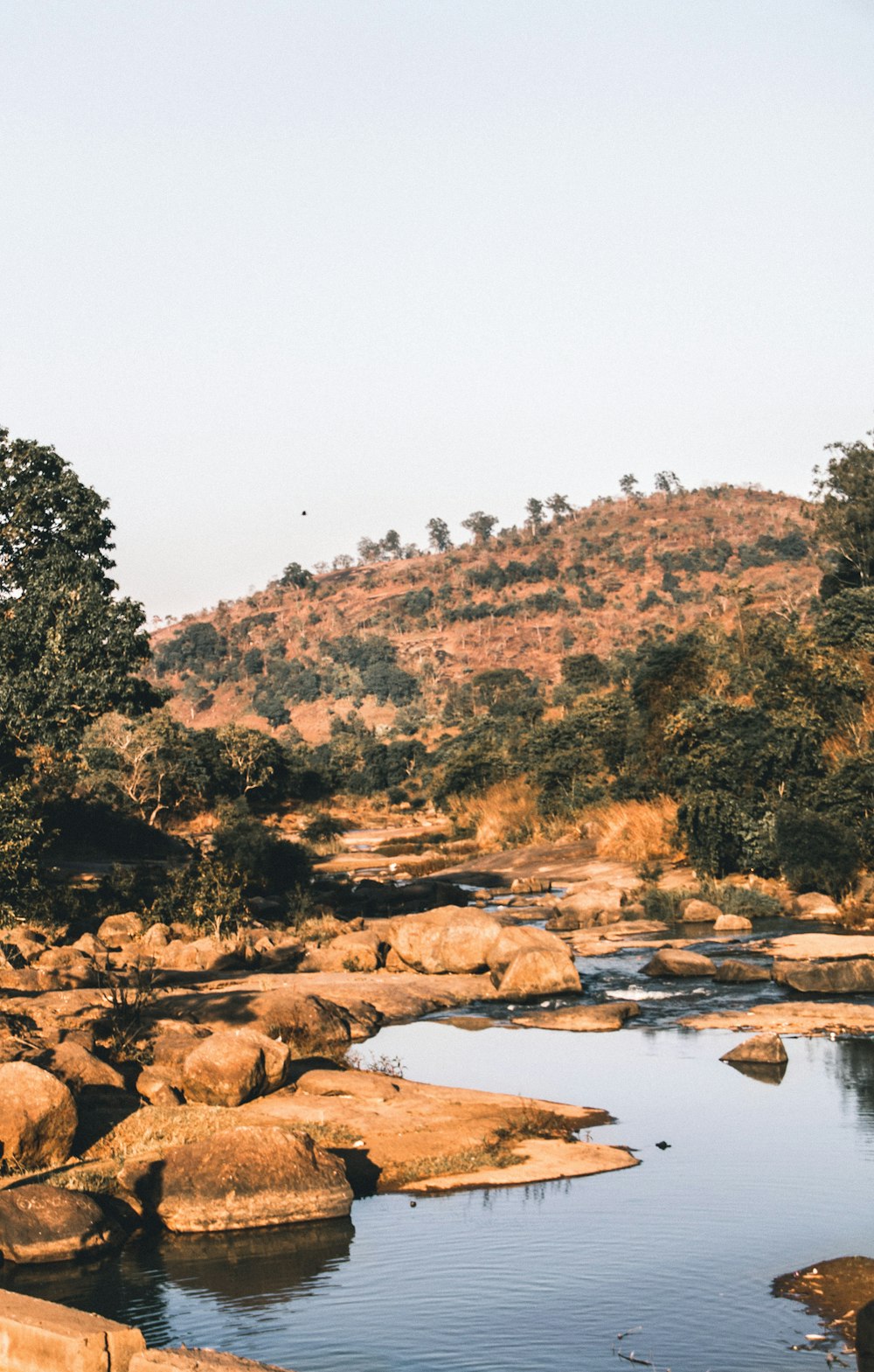 body of water across brown hills during daytime