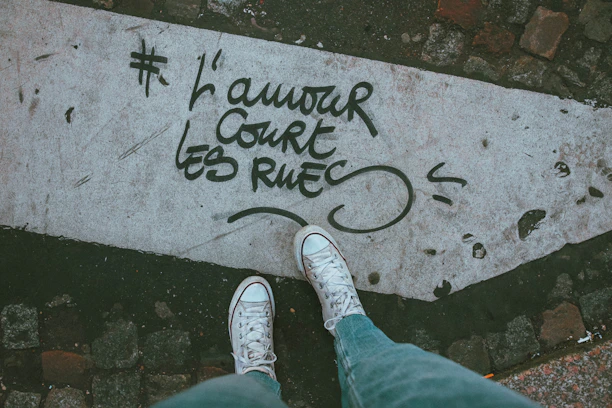 Close-up of trendy sneakers on a concrete sidewalk with graffiti art in the background.