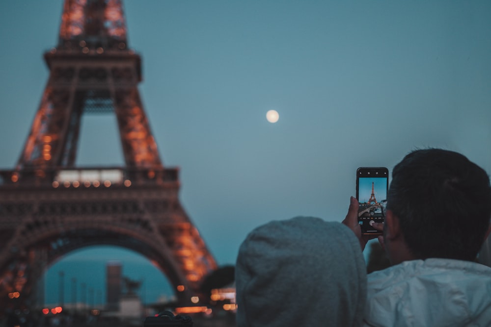 man taking picture of eiffel tower
