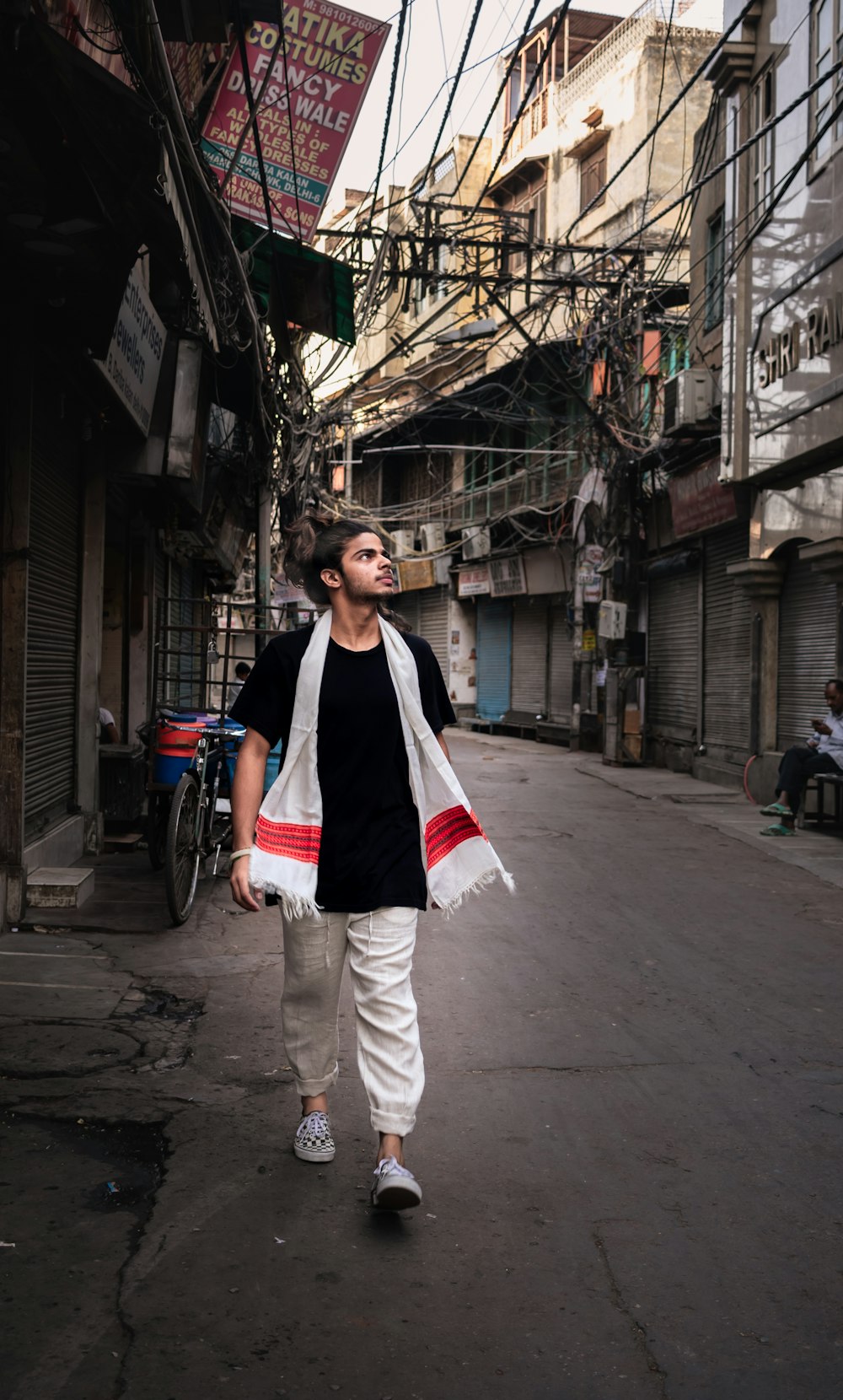man in black t-shirt and white pants with shawl during daytime