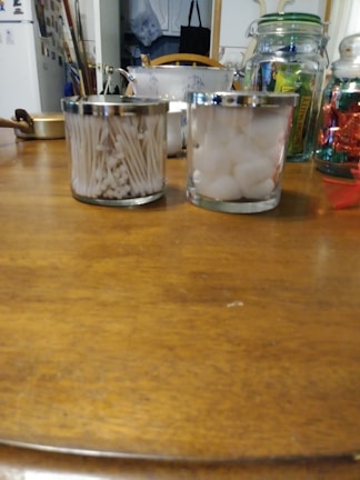 Cotton buds in a transparent container on a wooden table.