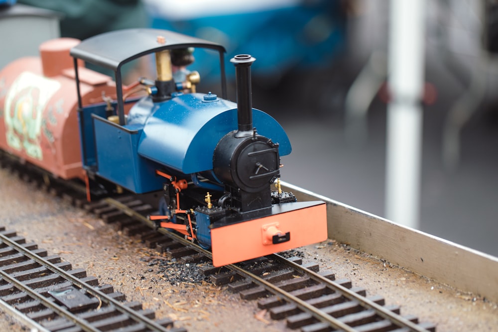 a toy train on a track with cars in the background
