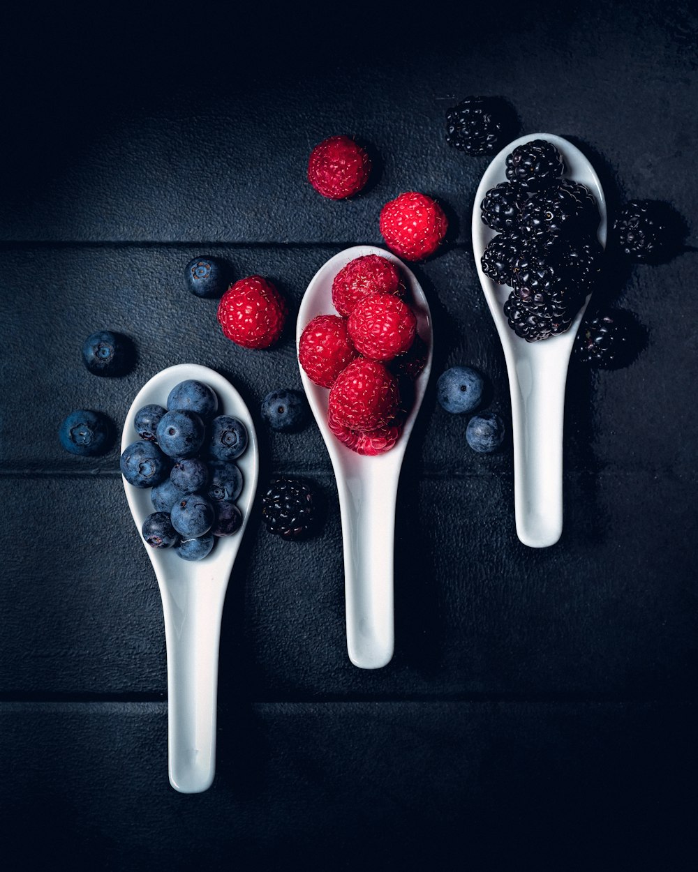 three ladles of berries on gray surface