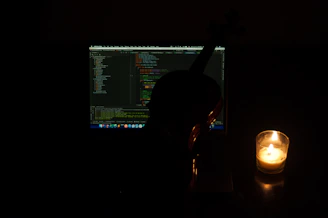 Close-up of hands coding on a laptop, with ancient manuscripts and a candle softly glowing nearby.