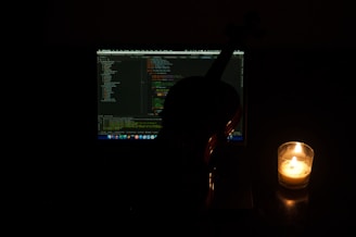 A candid shot of versavibe coding late at night, with soft light illuminating the screen and a guitar resting nearby.