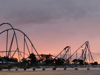 parked car lot beside roller coaster during golden hour