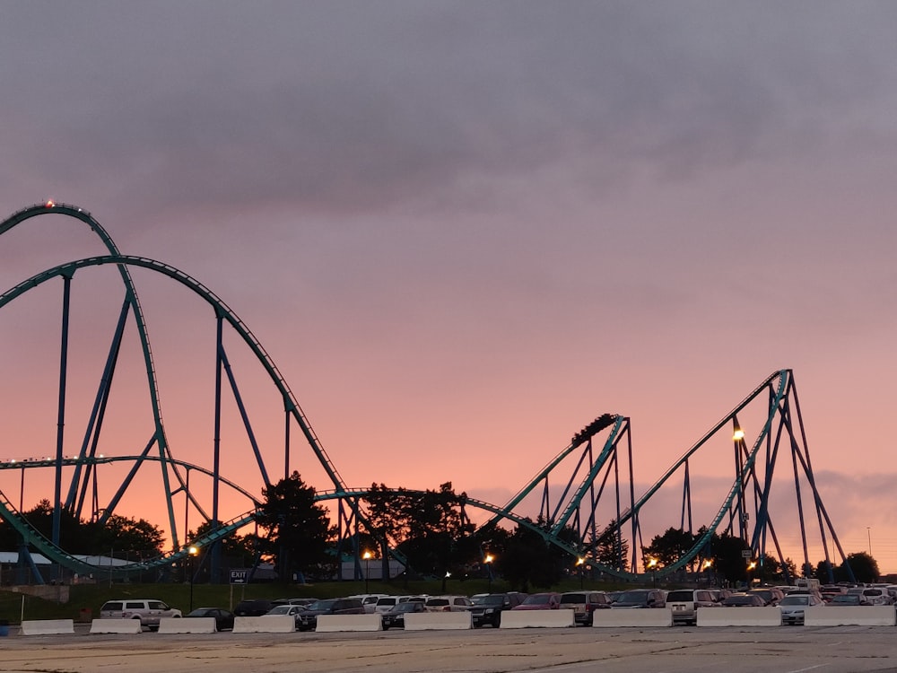 parked car lot beside roller coaster during golden hour