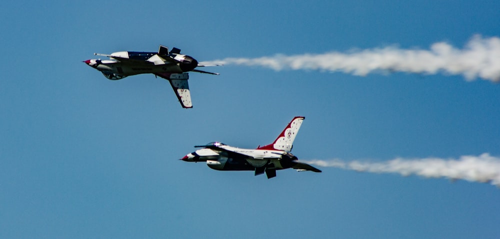 two gray and red air crafts with contrail