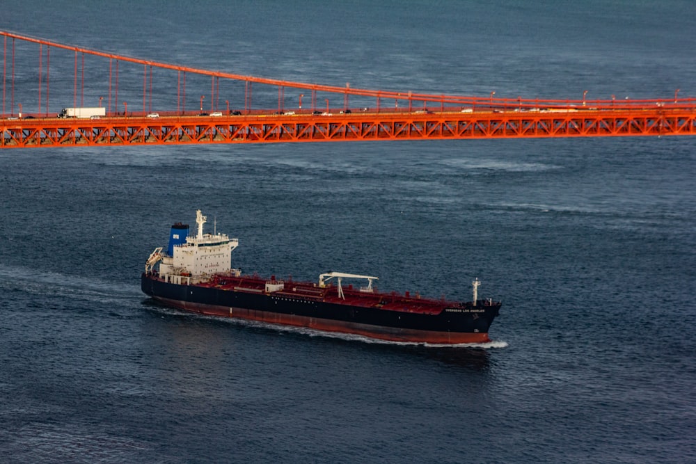 Schwarzes und rotes Schiff unter Brücke