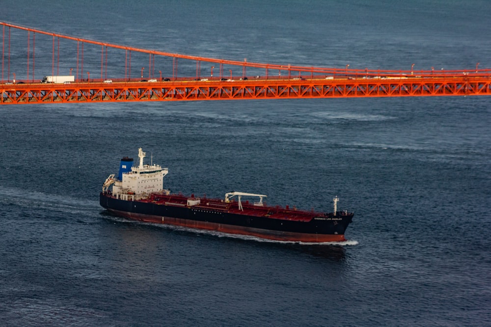 black and red ship under bridge