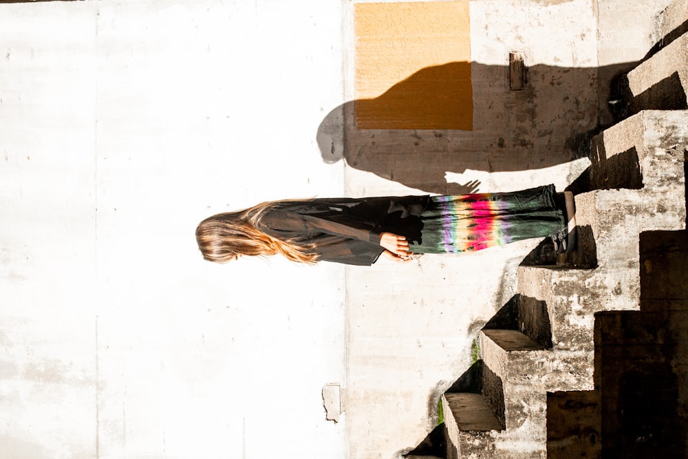 donna in camicia nera a maniche lunghe e gonna multicolore in piedi sulle scale