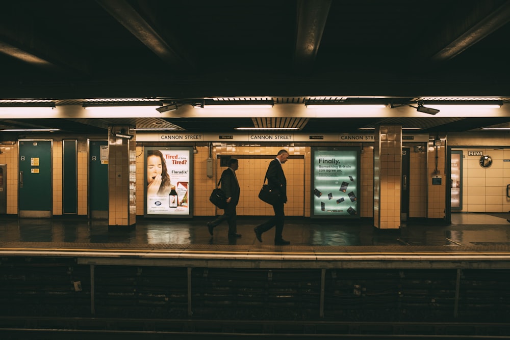 two men walking along subway train station