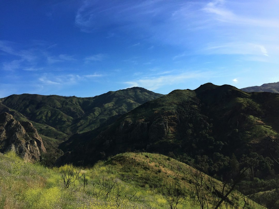 green and black hills under clear blue sky,