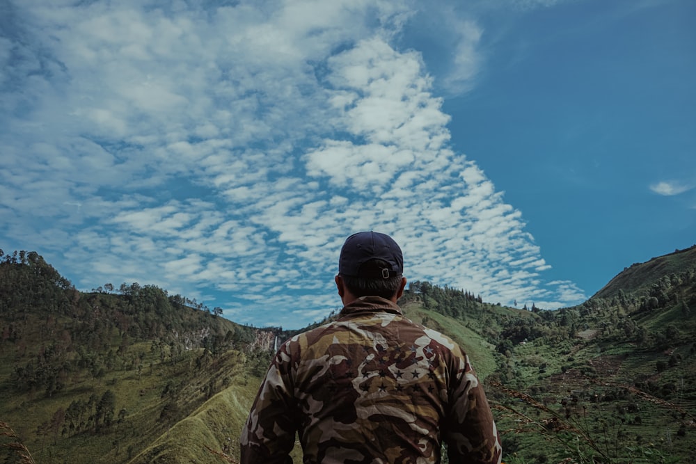 man in brown camouflage jacket standing on top of hills