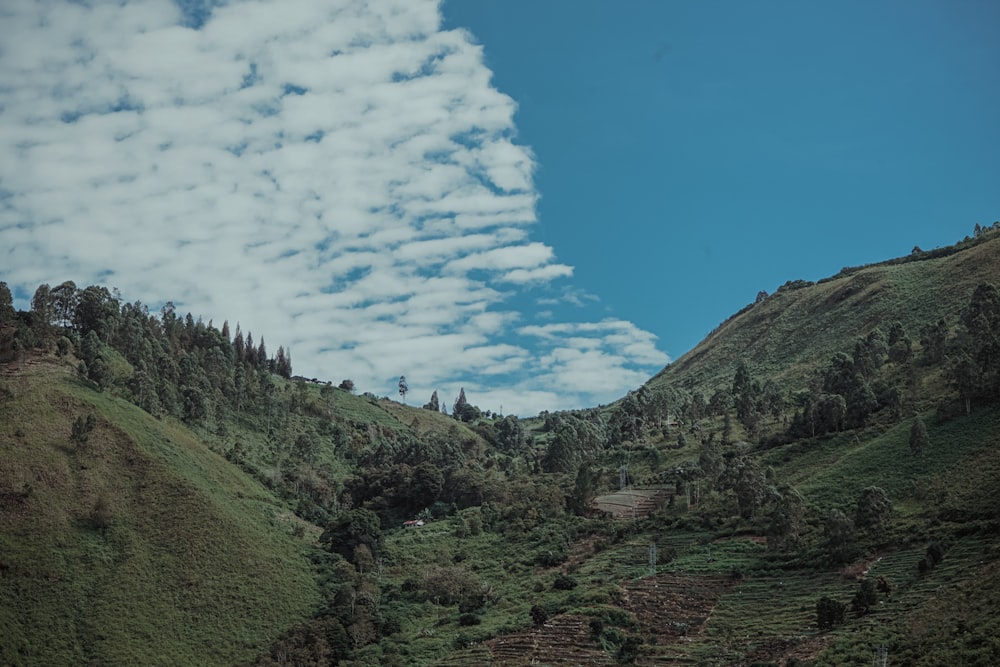 white clouds hovering above green mountain