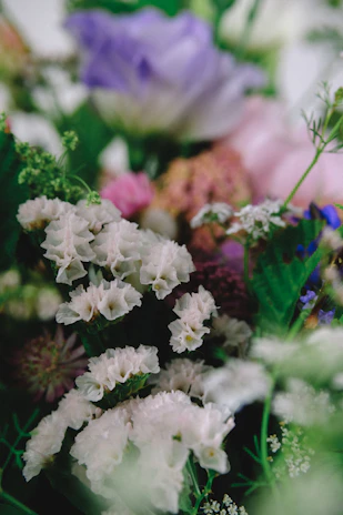 A vibrant bouquet of lilac, magenta, and green flowers arranged elegantly on a white background.
