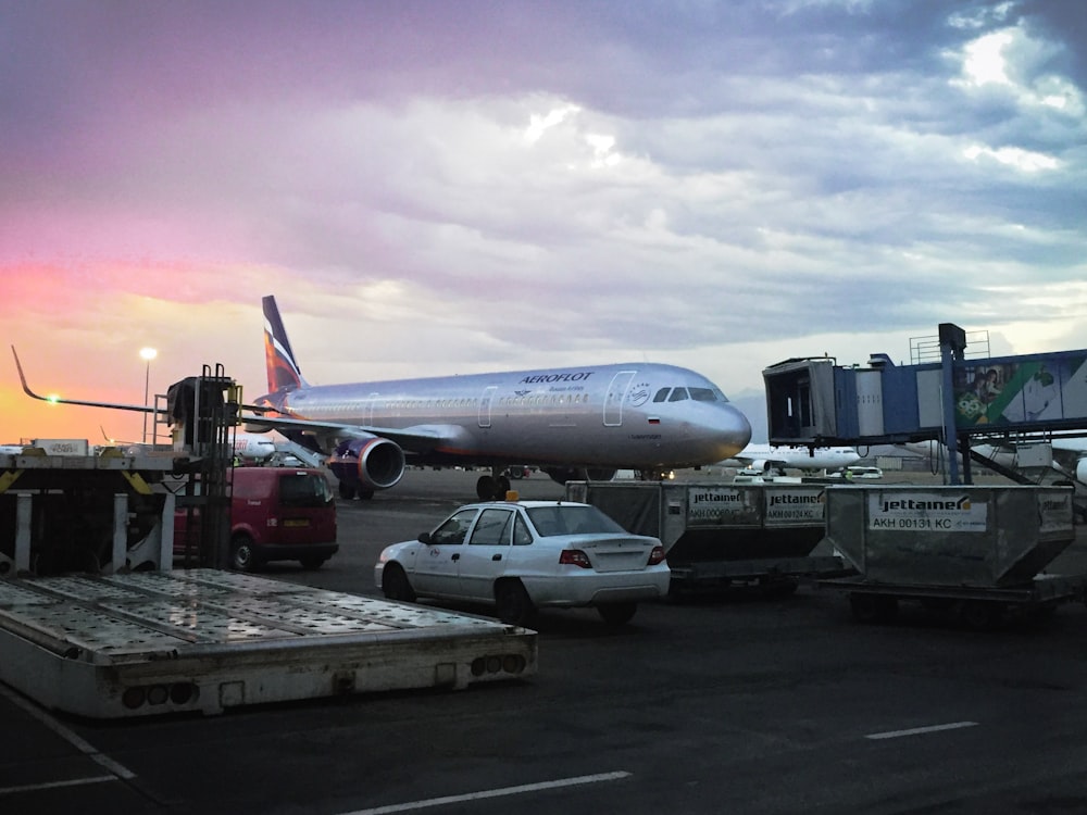 white airplane near different vehicles on railway under white skies