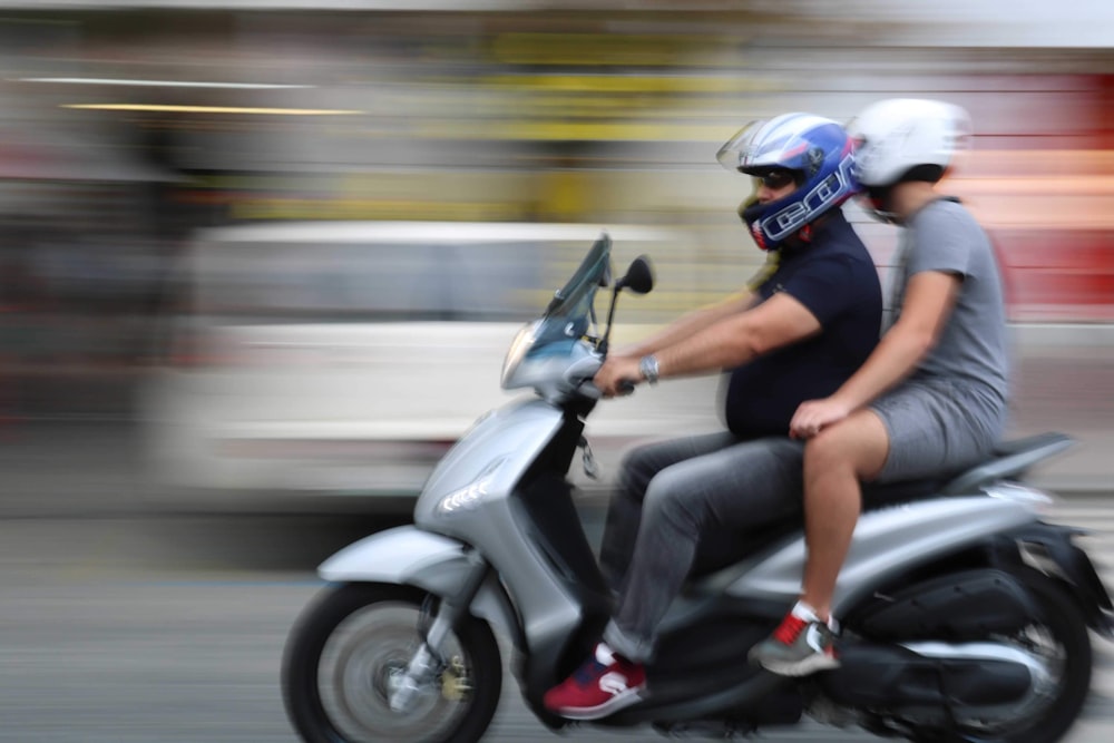 two men riding gray motor scooter
