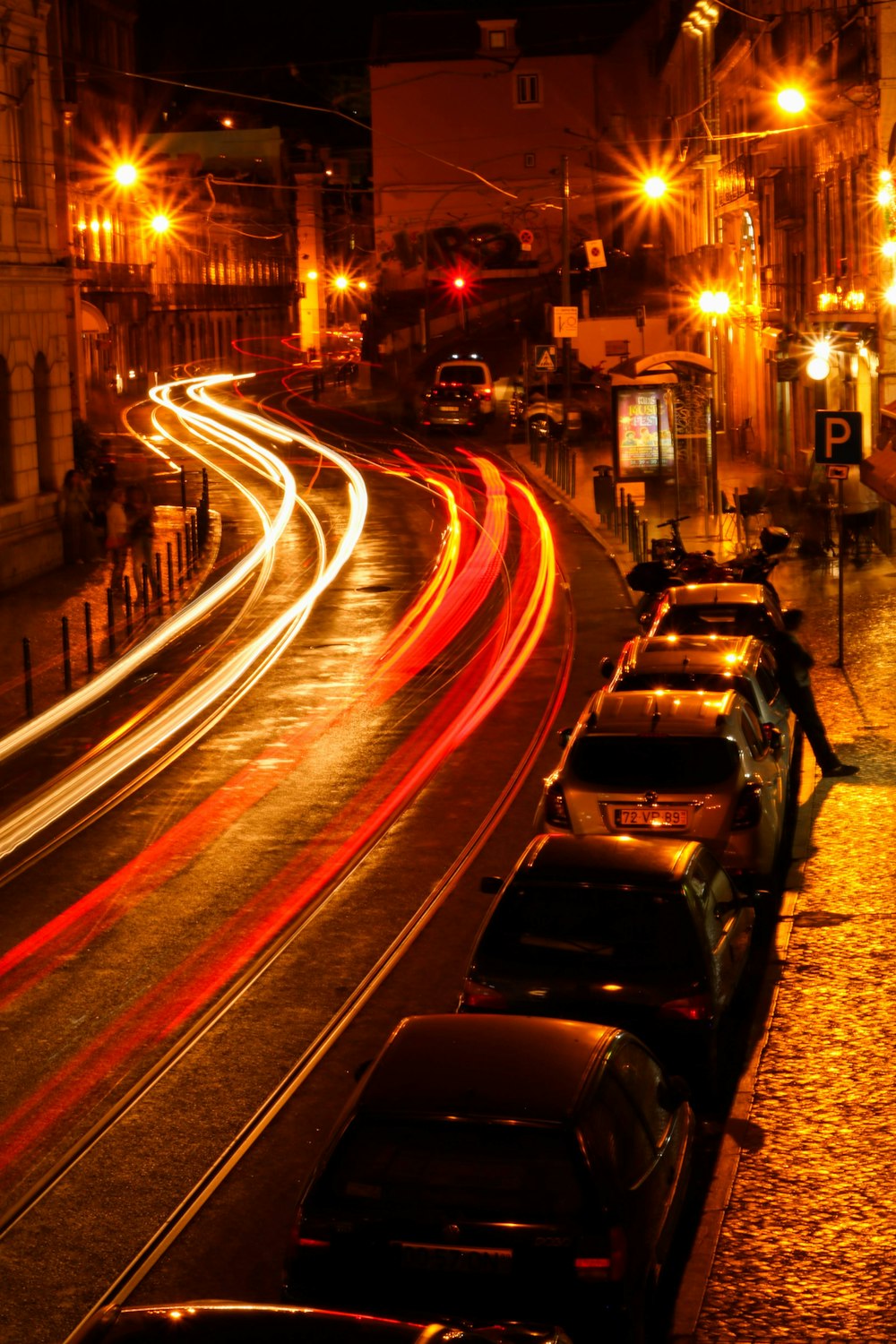 time lapse photography of different vehicles on road viewing lighted street lights during night time