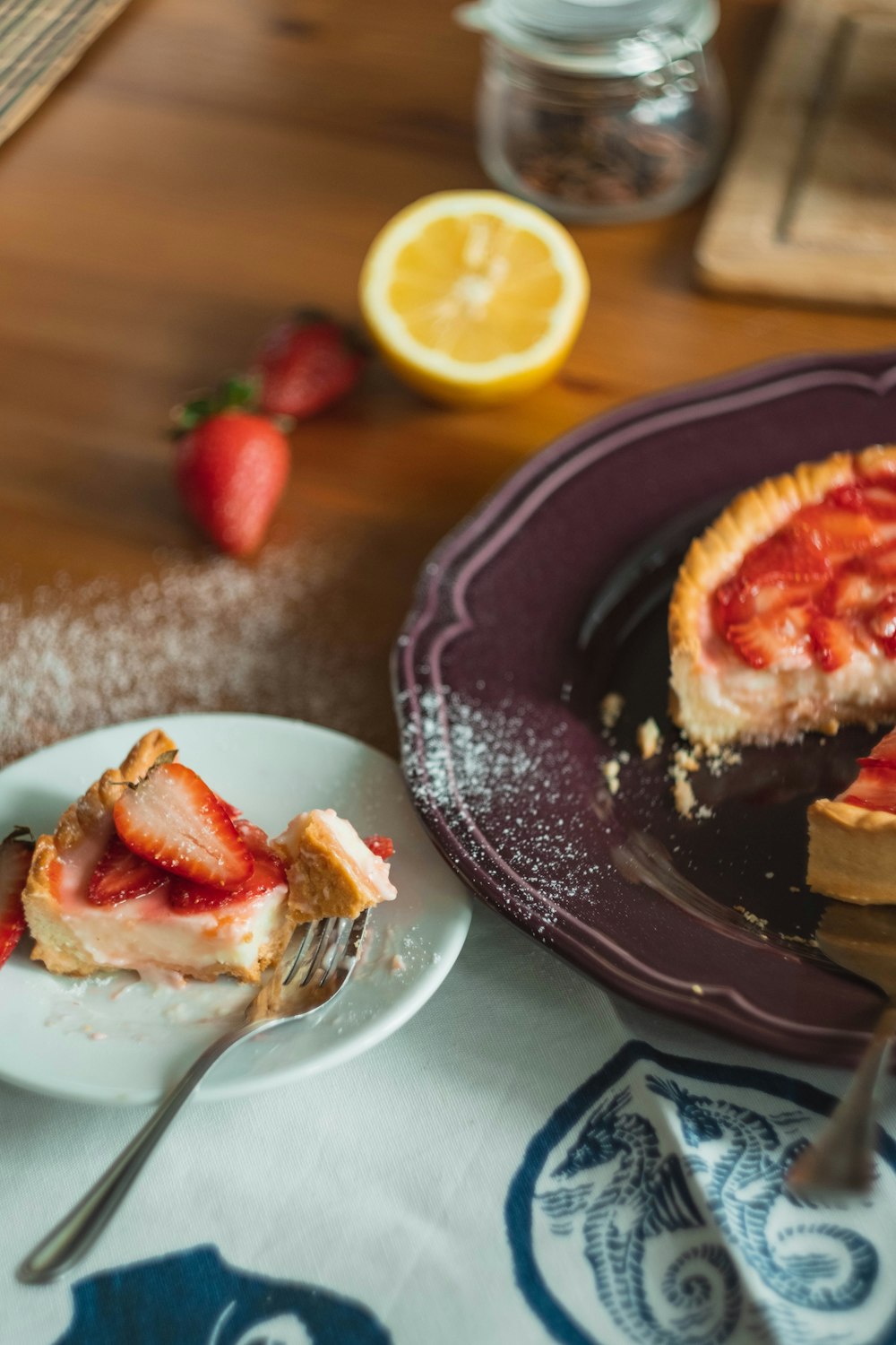 strawberry pie slice on saucer beside plate plate with pie