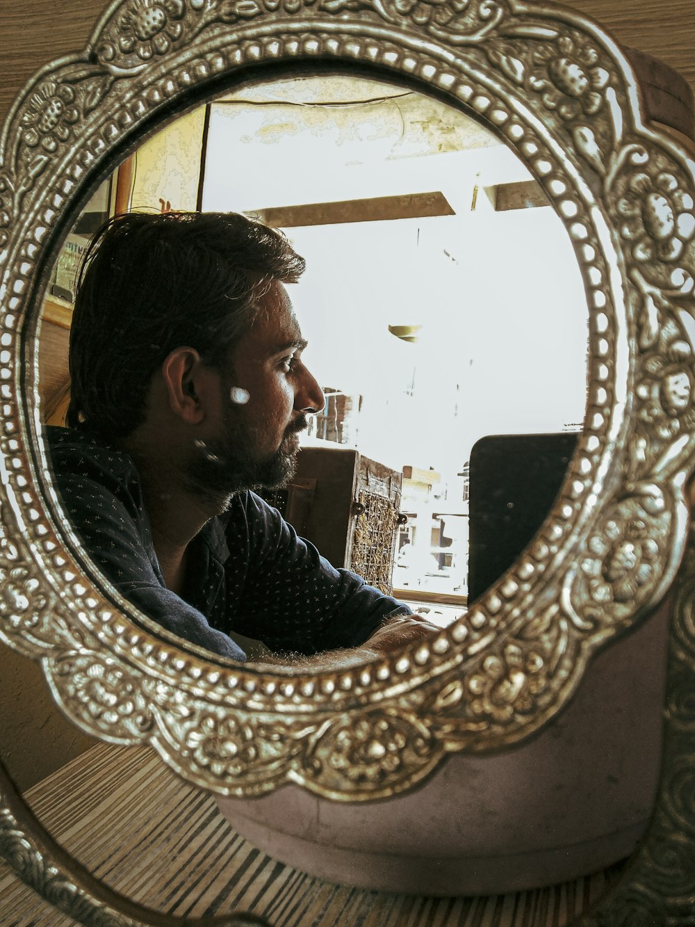 man's reflection on ornate gold-colored floral framed mirror