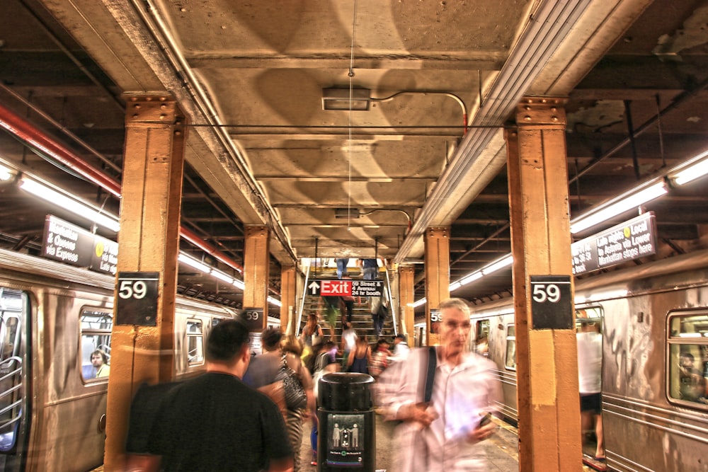 panning photo of people walking beside trains