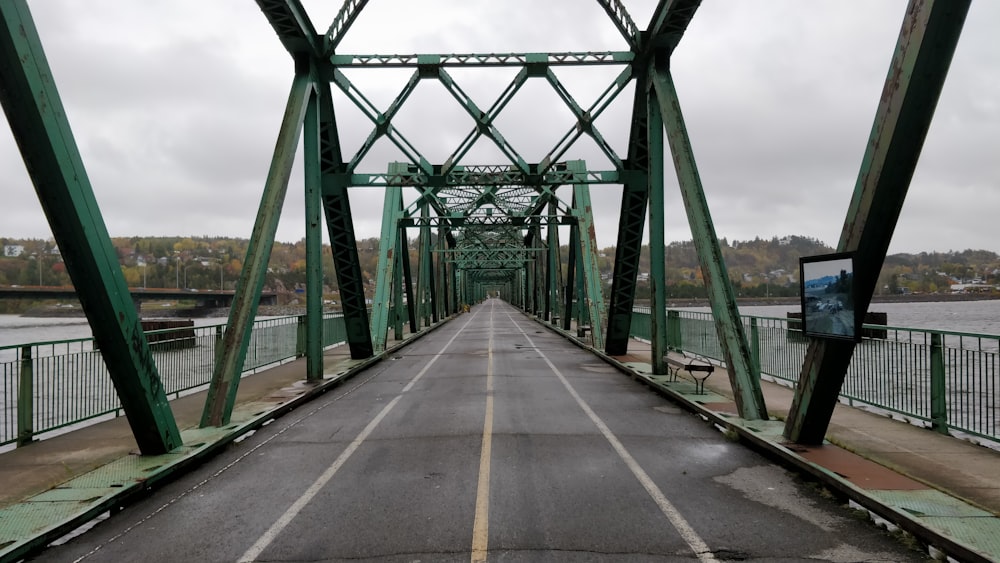 gray concrete bridge with no vehicle viewing sea and mountain