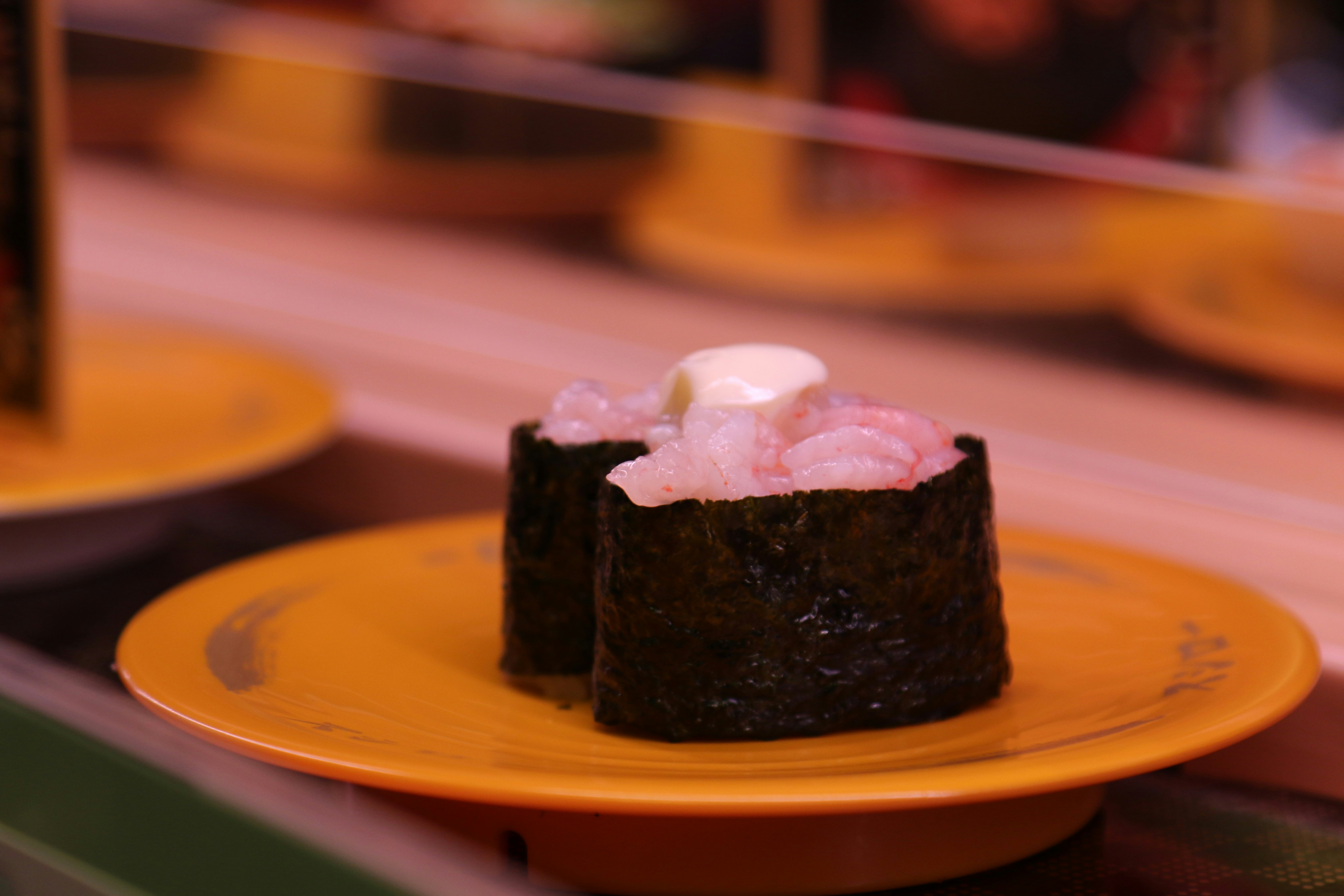 Gunkan di piring oranye di atas conveyor belt