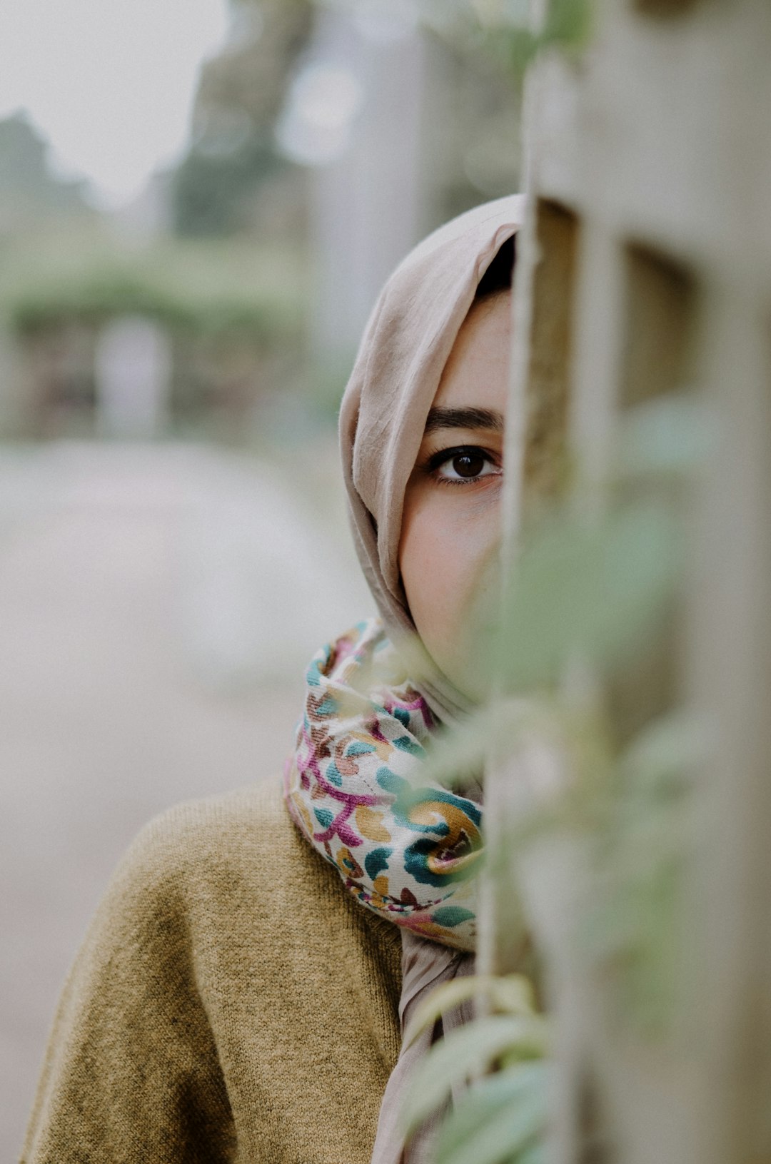 selective focus of woman wearing gray hijab hiding on wall